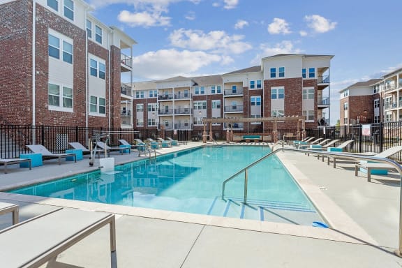 pool with lounge chairs and apartment buildings in the background at The lofts in slidell