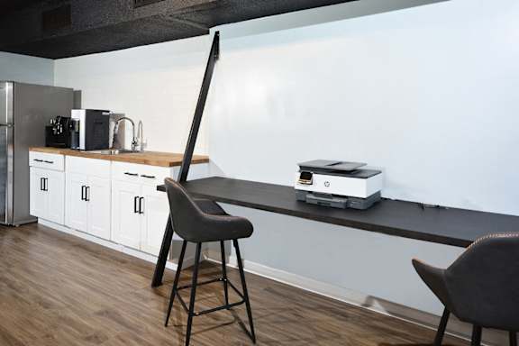 a kitchen with a counter top with a printer and a chair at Capital Flats & Magnolia Square Apartments, North Carolina, 27601