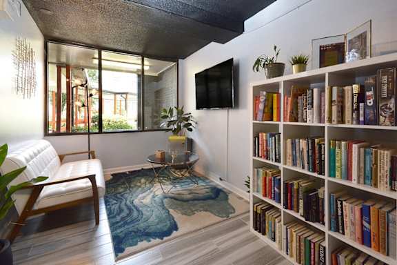 a living room with a bookshelf full of books   and a window at Capital Flats & Magnolia Square Apartments, North Carolina, 27601