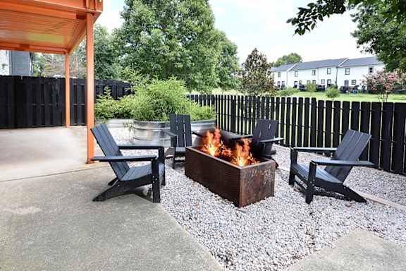a patio with a fire pit and chairs and a black fence at Capital Flats & Magnolia Square Apartments, Raleigh, 27601