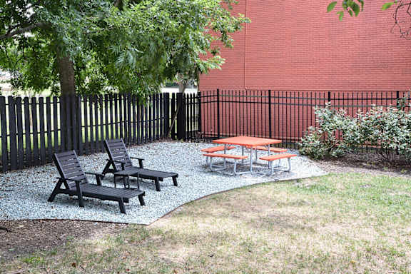 a patio with two tables and benches in front of a fence at Capital Flats & Magnolia Square Apartments, Raleigh, NC, 27601