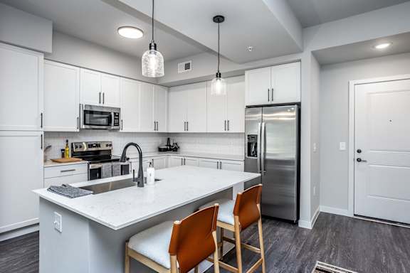 Quartz countertops, trendy tile backsplash and matte black fixtures in model