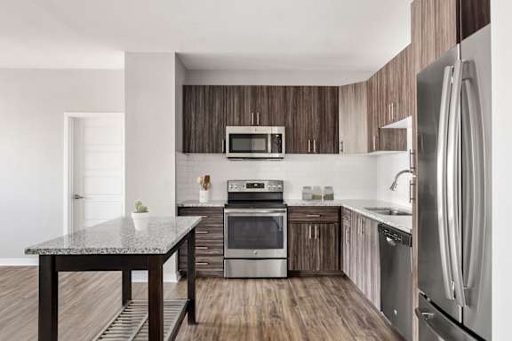 A modern kitchen with a granite table and stainless steel appliances.