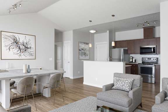 A modern dining room with a white table and grey chairs.