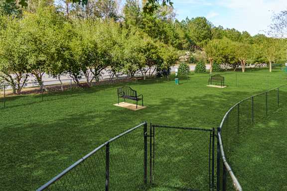 A park with a green lawn and a fence.