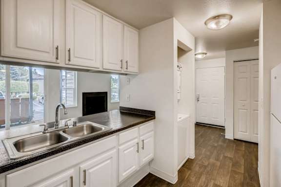 A kitchen with white cabinets and a black counter top.
