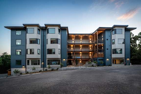 A modern apartment building with a parking lot in front.