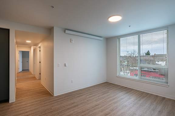an empty living room with a large window and wood flooring