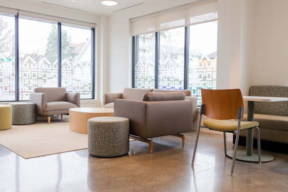 a living room with couches chairs and tables and windows