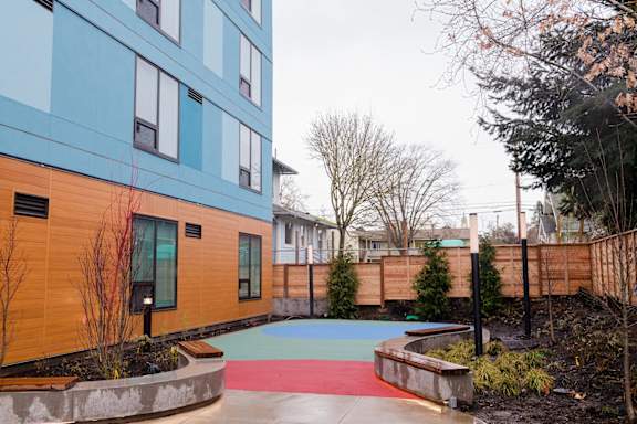 a courtyard with a blue building and a red and blue sidewalk