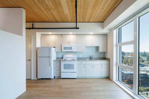 A modern kitchen with white appliances and wooden floors.