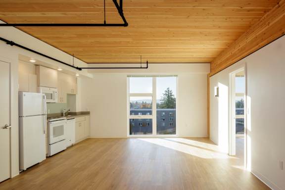 A kitchen with white appliances and wooden floors.