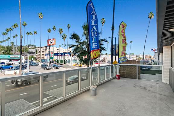 A view of a parking lot with a clear blue sky and palm trees in the background in a live/work apartment at Fusion Hollywood.