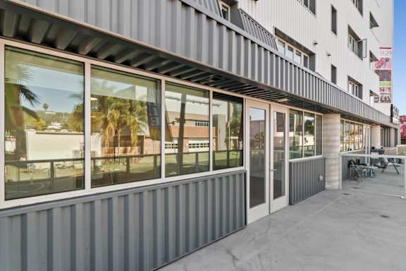 A building with a grey facade and large windows overlooking a patio in a live/work apartment at Fusion Hollywood.