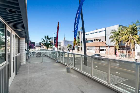 A balcony with a railing and a few chairs and umbrellas in a live/work apartment at Fusion Hollywood.
