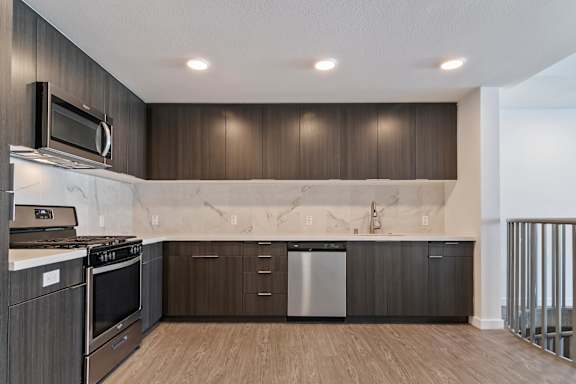 A modern kitchen with dark wood cabinets and stainless steel appliances at Fusion Hollywood.
