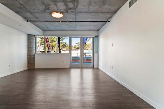 A large empty room with a view of the outside through the windows in a loft apartment at Fusion Hollywood.