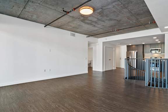 Living room and kitchen at Fusion Hollywood with wooden floors and a concrete ceiling.