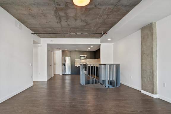 Living room and kitchen at Fusion Hollywood Apartments with a concrete ceiling and wooden floors.
