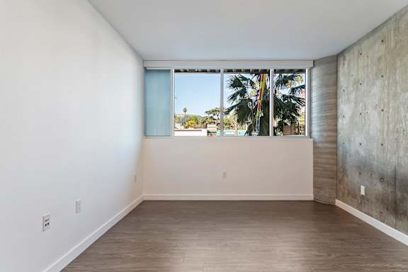 A bedroom with a large window and a concrete wall at Fusion Hollywood Apartments.