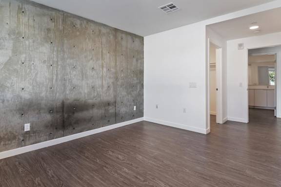 A bedroom with a concrete wall and wooden floor at Fusion Hollywood.