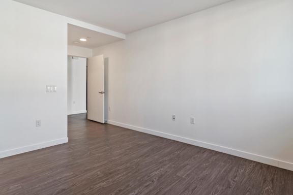 A bedroom with a wooden floor and a white door.