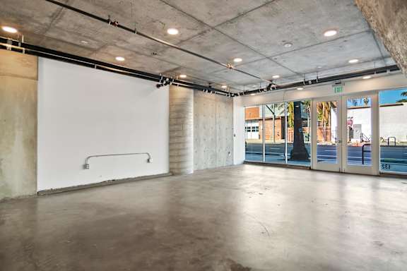 A large, empty live/work space room with a white wall and a concrete floor at Fusion Hollywood.