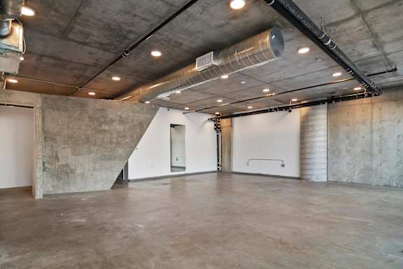 A large, empty room with concrete walls and a concrete floor in a live/work apartment at Fusion Hollywood.