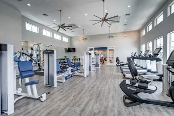 A spacious gym with a variety of equipment and a ceiling fan.
