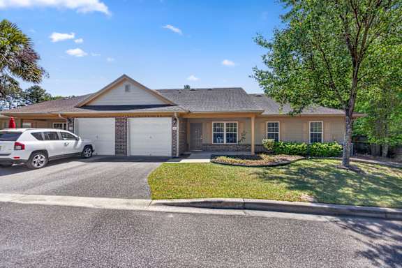 A house with a white garage door and a tree in front.
