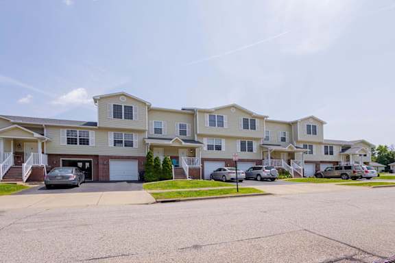 A row of townhouses with cars parked in front.