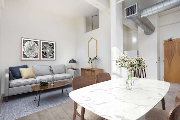 A modern living room with a grey sofa, a white marble table, and a grey carpet.