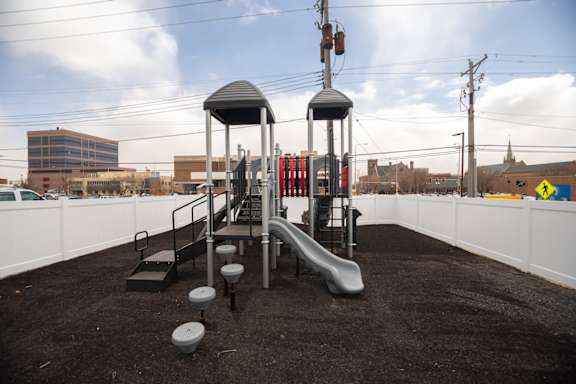 A playground with a slide and a blacktop surface.