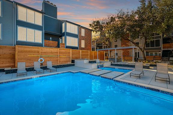 A swimming pool surrounded by chairs and a wooden fence.