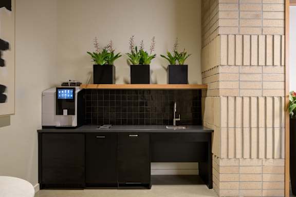 a lobby with a black counter with a coffee machine and plants at The Lucy Boise Apartments, Idaho, 83702