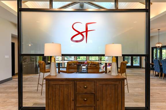 A reception desk with a glass wall and a logo on it.