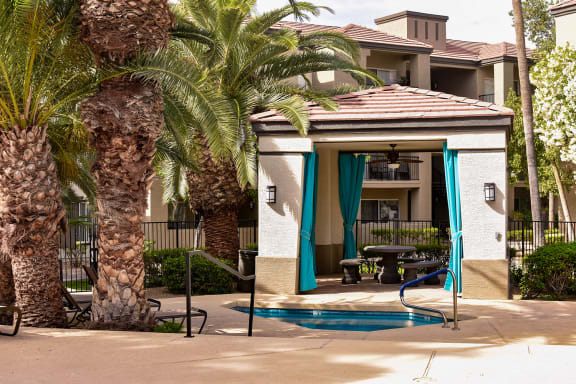 Shaded poolside ramada near spa and BBQ grill area