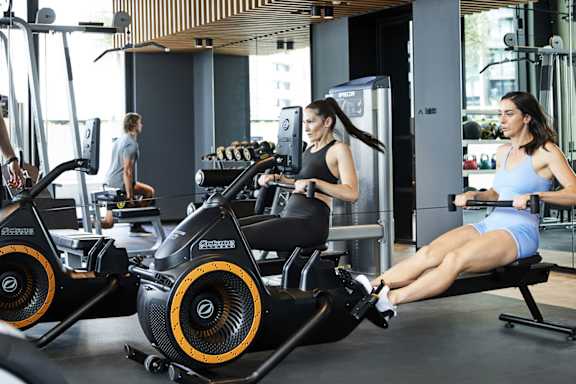 A woman is working out on a rowing machine in a gym.