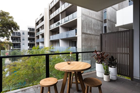 a balcony with a table and three stools overlooking an apartment building