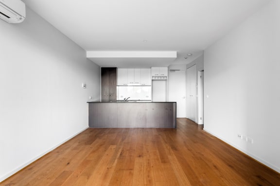 a living room and kitchen with white walls and wood floors