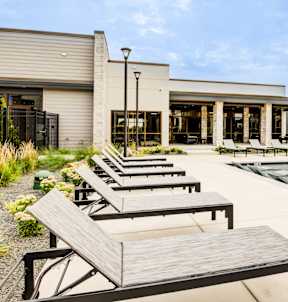 A poolside area with sun loungers and a building in the background.