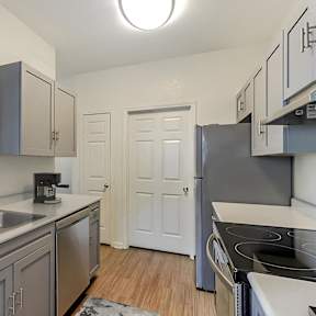 A kitchen with a sink, stove, and cabinets.