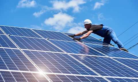 A worker is installing solar panels on a roof.