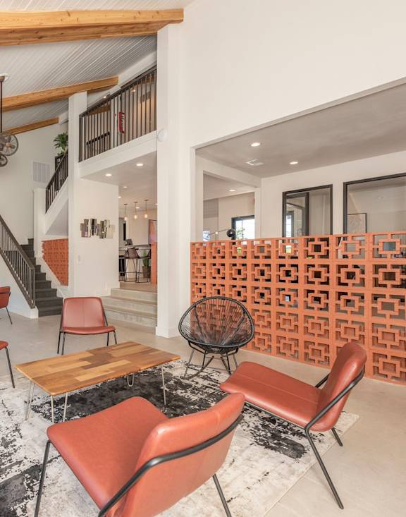 Fusion 35 Apartments clubhouse area with orange chairs, wooden tables, and wooden beams on the ceiling.