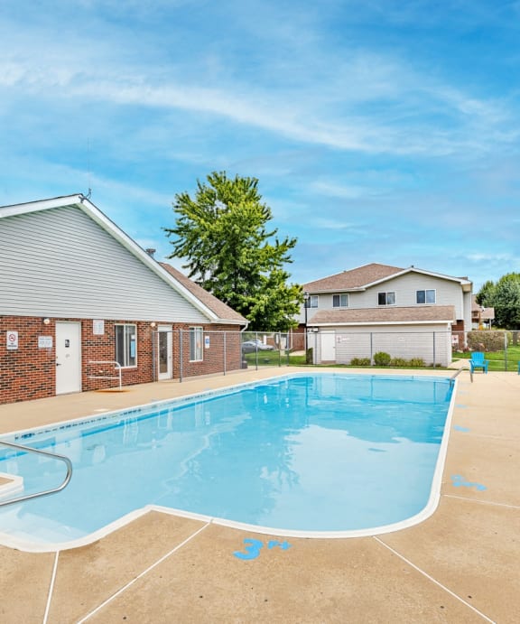 our resort style swimming pool is next to our house with chairs and a patio
