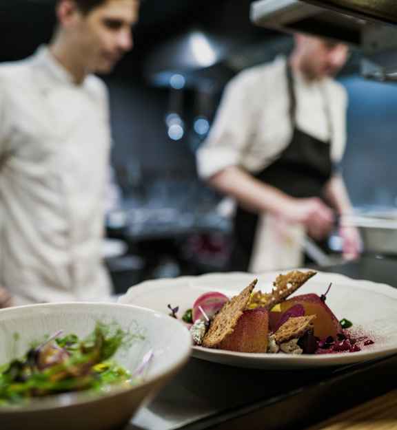 a plate of food on a counter with a chef in the background