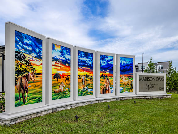 A row of four large paintings of horses in a field with the text "MADISON OAKS" on the right.