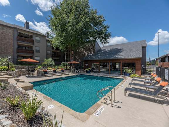 Fusion 35 Apartments pool with lounge chairs and buildings surrounding it.