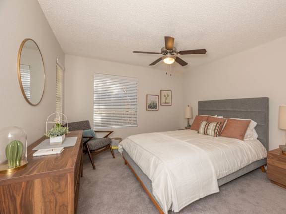 Fusion 35 Apartments staged bedroom with ceiling fan, bed, nightstand, and dresser.