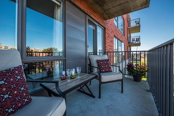 a balcony with a couch and chairs and a table with wine glasses